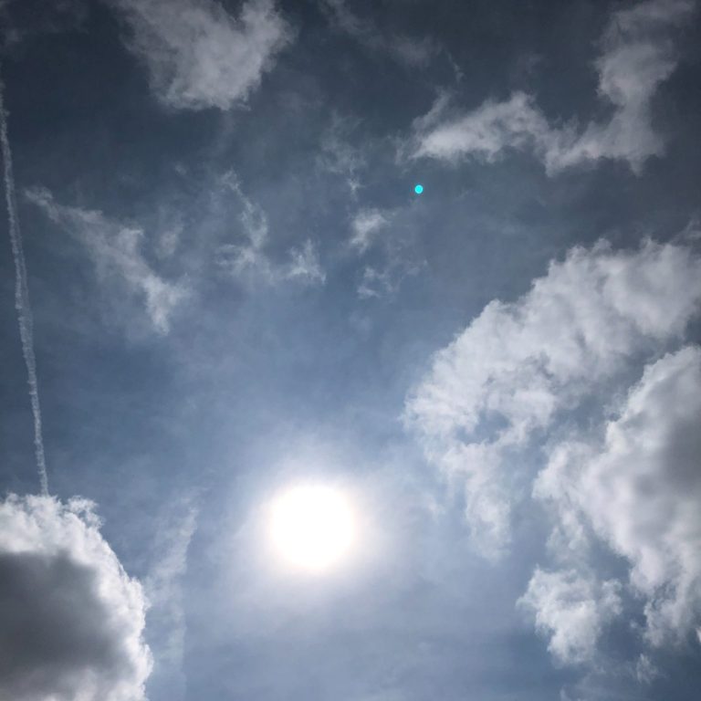 Heller Himmel mit Sonnenstrahlen, Wolken und einem leichten Schleier aus Dunst.