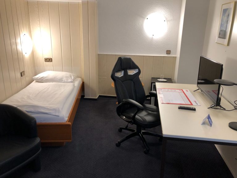 Schlafzimmer mit Einzelbett, Schreibtisch, Bürostuhl und Sessel.
