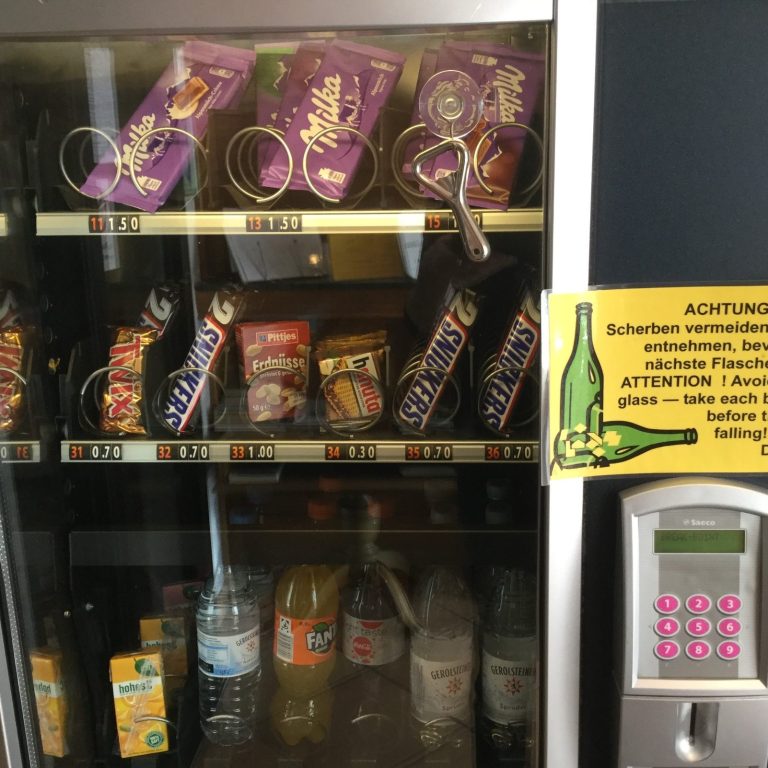 Warenautomat mit Snacks und Getränken, darunter Chips, Schokolade und Limonade im Eingangsbereich