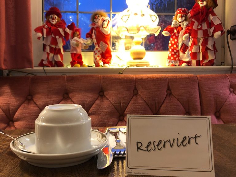 Tisch mit reserviertem Schild, Geschirr und dekorativen Figuren im Hintergrund.