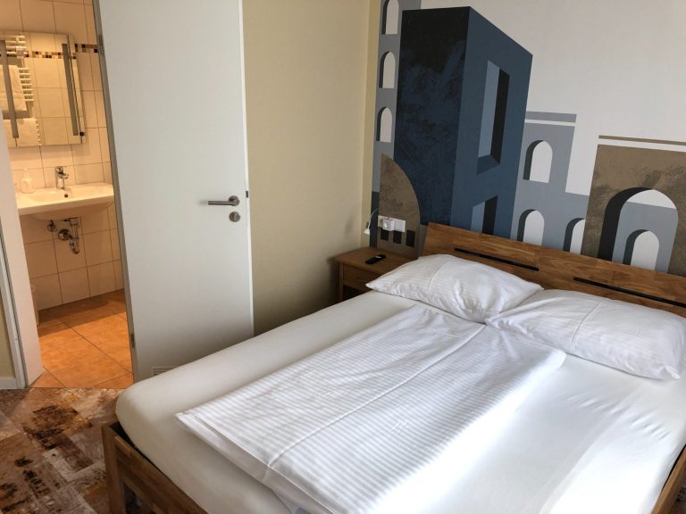 Helle Hotelzimmer mit einem Bett und angrenzendem Badezimmer.